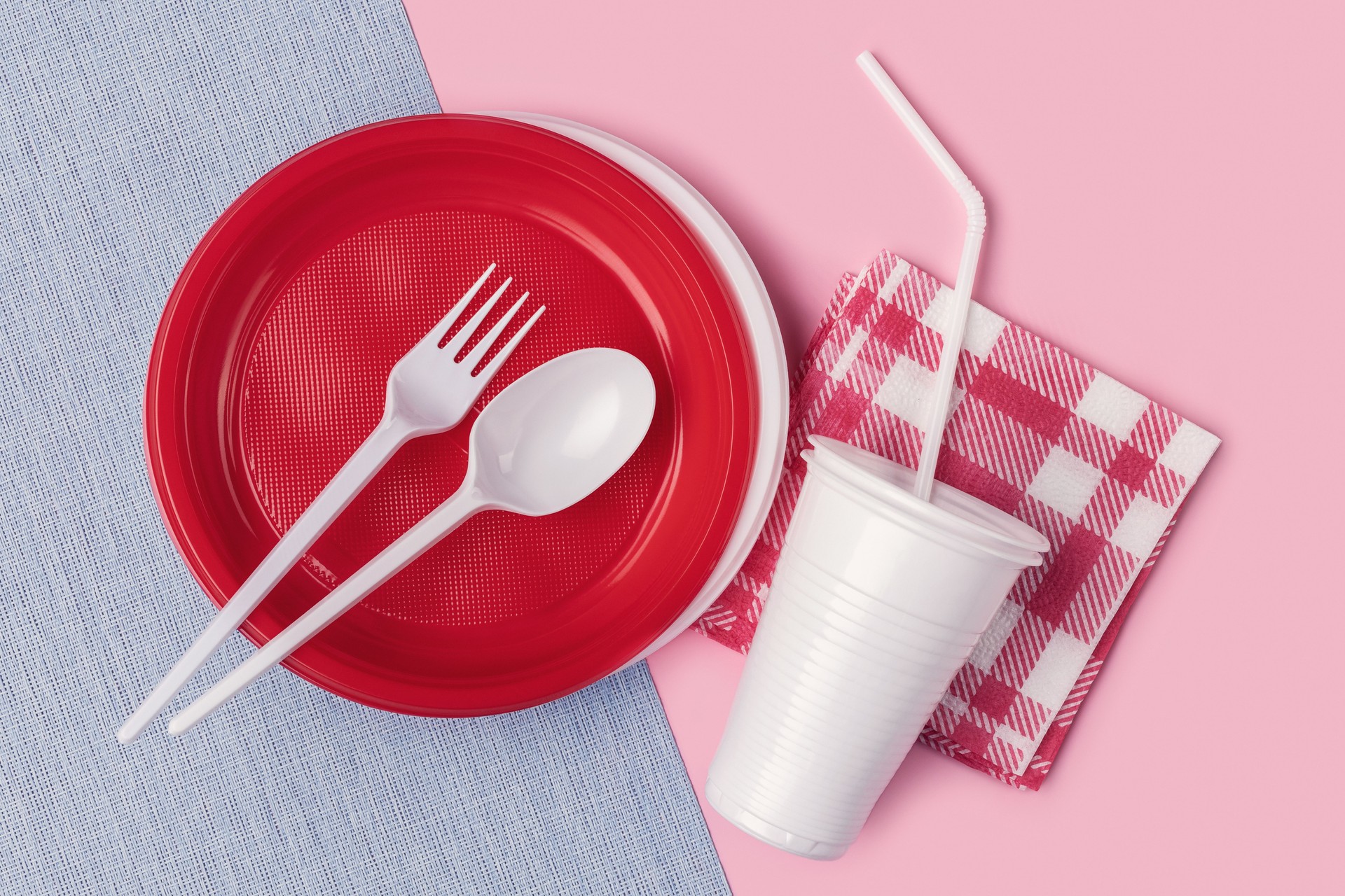 Disposable colored plastic tableware on a two-color background.