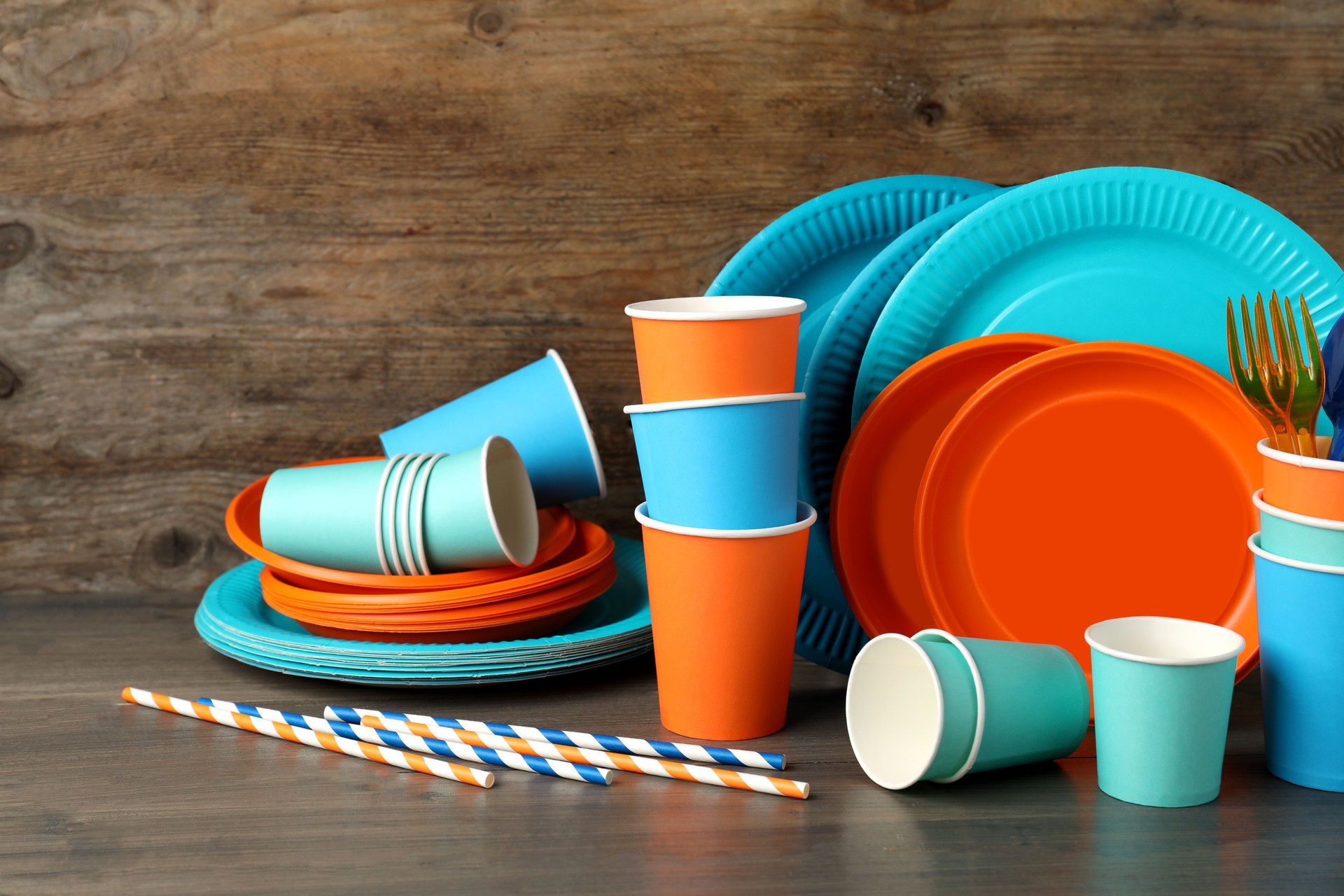 Set of bright disposable tableware on wooden table